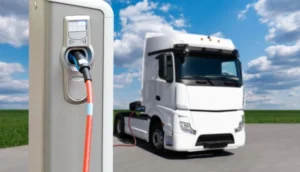 Electric HGV truck connected to a charging station under a blue sky