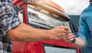 Two people exchanging keys in front of a red HGV truck