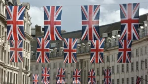 Rows of Union Jack flags hang across a street lined with historic buildings