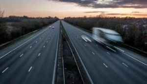 Nearly empty dual carriageway at dusk with a blurred truck speeding down one side