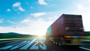 A cargo truck speeds down a highway with "2023" marked on the road