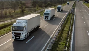 Multiple white cargo trucks driving in formation on a multi-lane highway