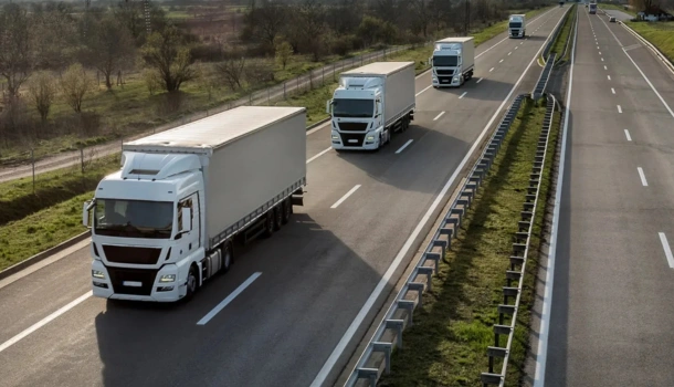 Multiple white cargo trucks driving in formation on a multi-lane highway